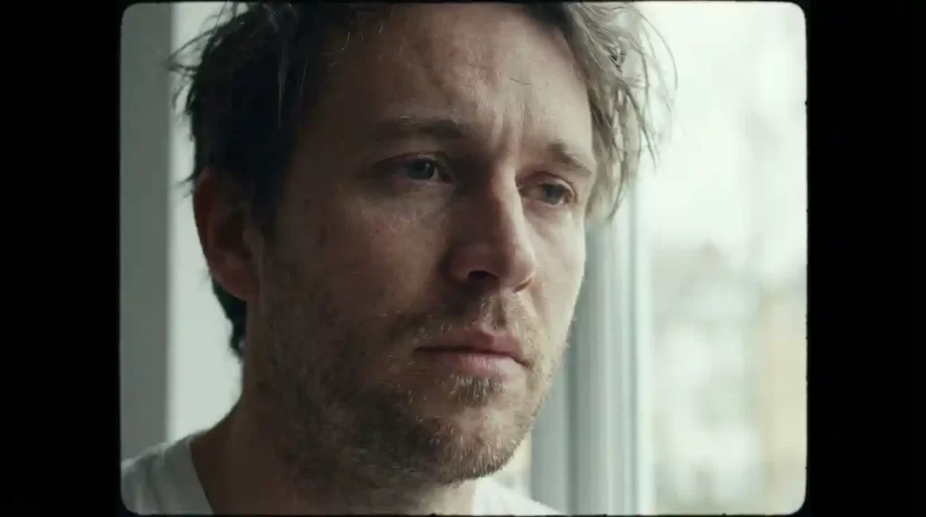 A cinematic shot in the 4:3 aspect ratio, where the tall frame creates an intimate focus on the actor's face