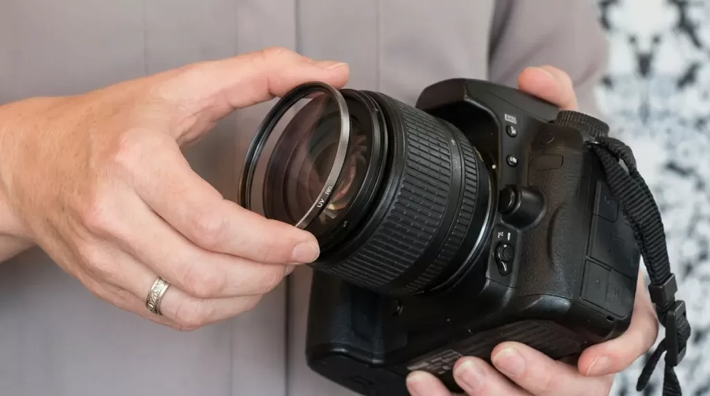 Photographer mounting a UV protection filter on a DSLR lens