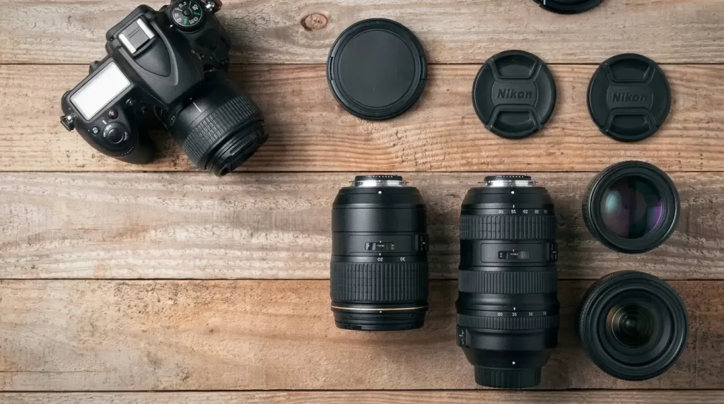 A DSLR camera with interchangeable lenses arranged on a wooden table