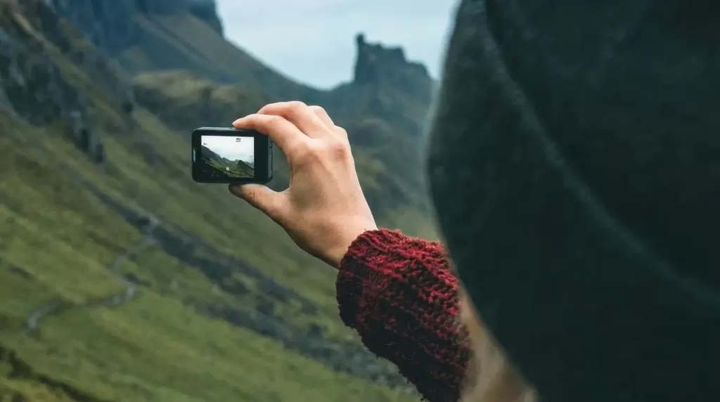 Akaso Brave action camera held up to film landscape