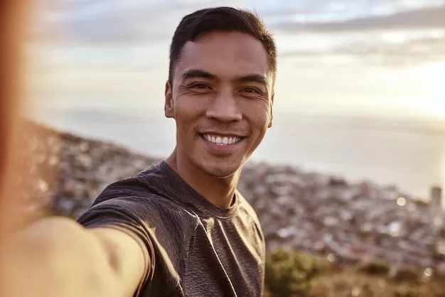 man taking selfie with front camera outdoors