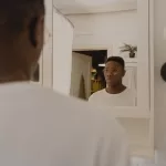 man checking reflection in bathroom mirror