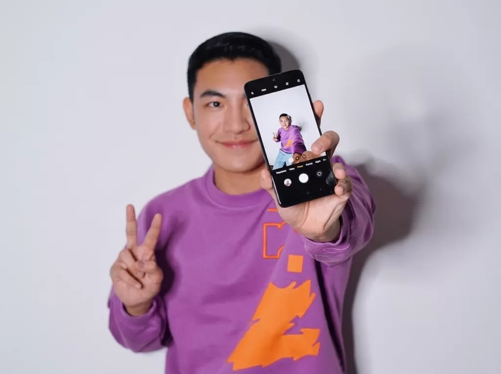 man using back camera on smartphone for selfie