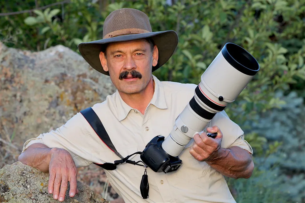 Photographer holding DSLR with telephoto lens outdoors