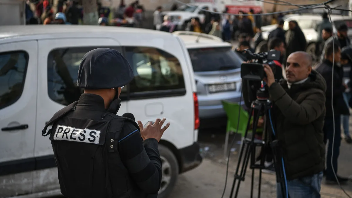 Press photojournalist in protective vest working in a conflict zone