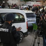 Press photojournalist in protective vest working in a conflict zone