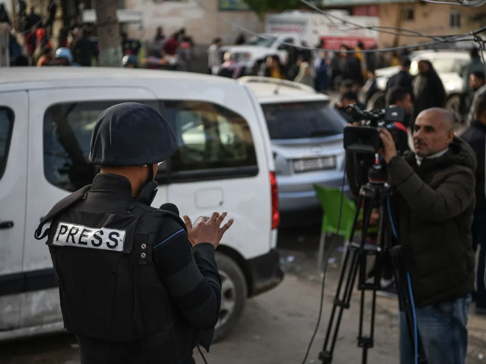 Press photojournalist in protective vest working in a conflict zone