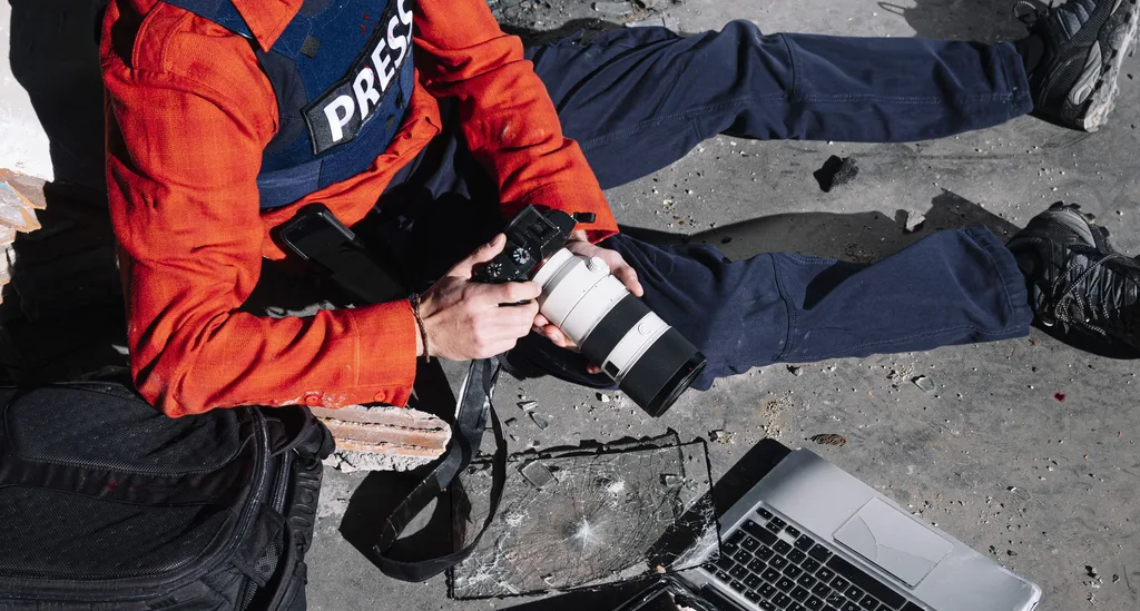 War photojournalist transmitting edited images from a laptop in the field
